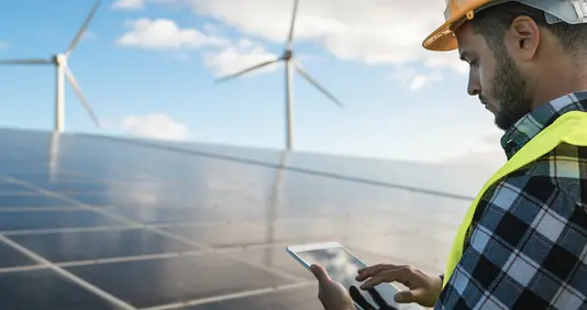 energie-sparen-haus-solar-photovoltaik-foerderung-07 Mann vor Solaranlage und Windrädern