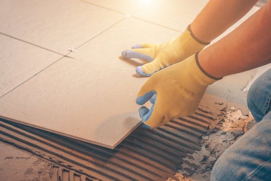 hausbau-haus-bauen-eigenleistung-handwerker-fliesen-02 Bauhelfer verlegt Fliesen